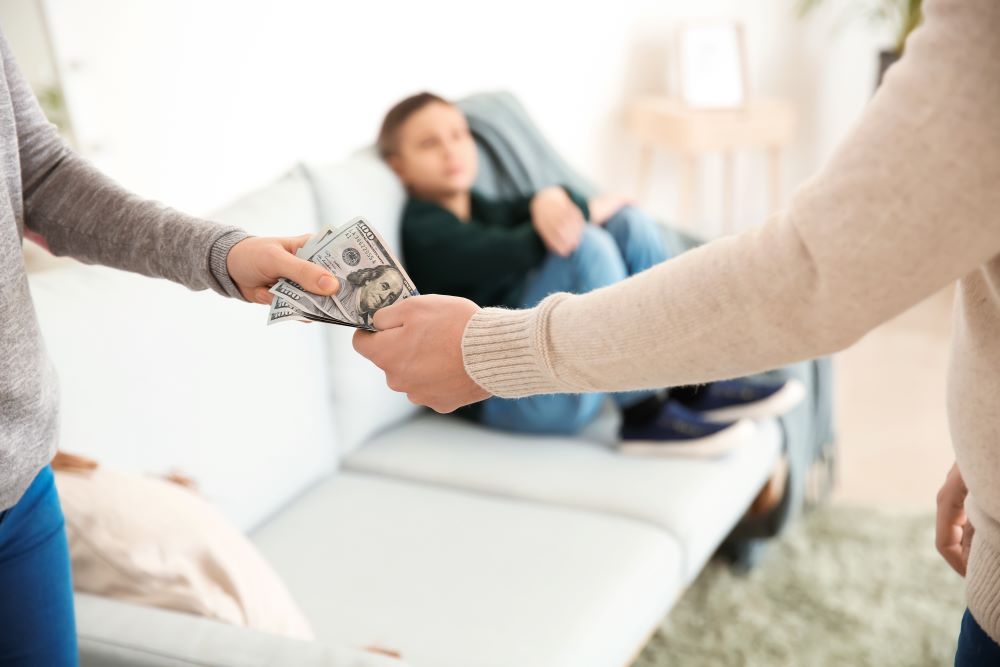 Child on couch with parents exchanging money