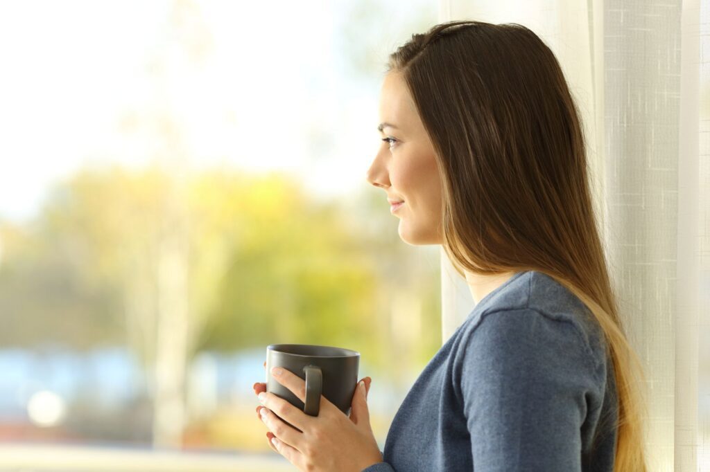 woman looking out window hopeful